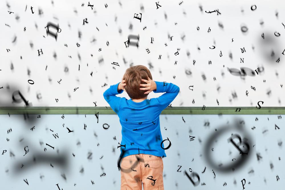 Enfant dyslexique face à un tableau couvert de lettres mélangées, illustrant la confusion visuelle causée par la dyslexie