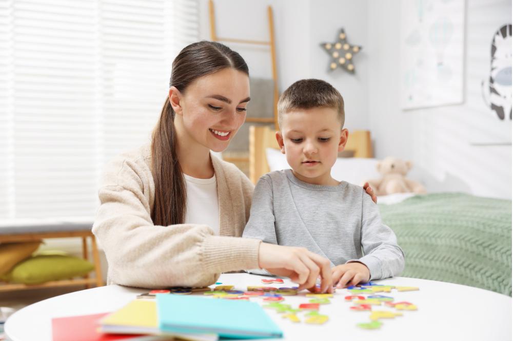 Orthophoniste accompagnant un enfant dans un exercice de manipulation de lettres colorées pour travailler la conscience phonologique